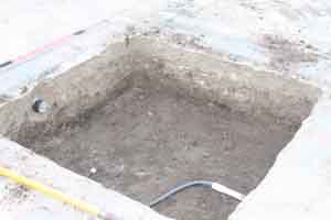 A square hole in a paver patio that is the size of the pondless water feature basin and has plumbing pipes